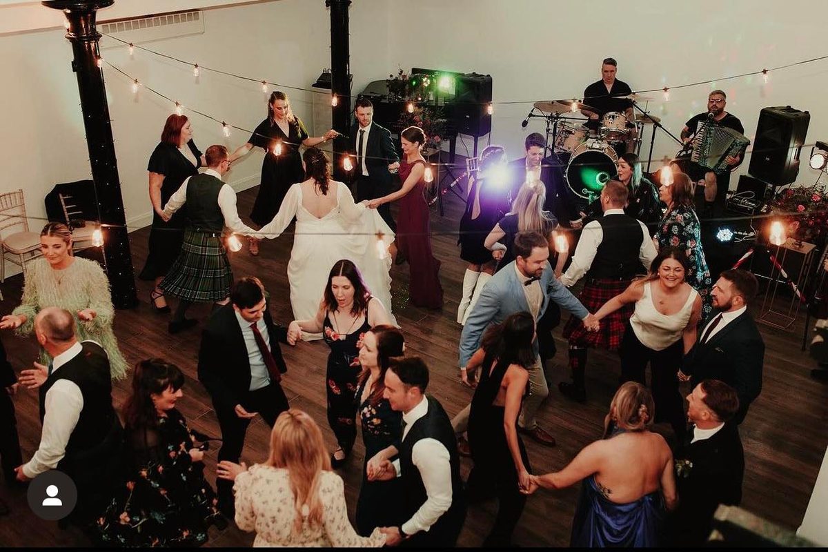 A wedding ceilidh in full swing — guests dancing in a circle as the band plays